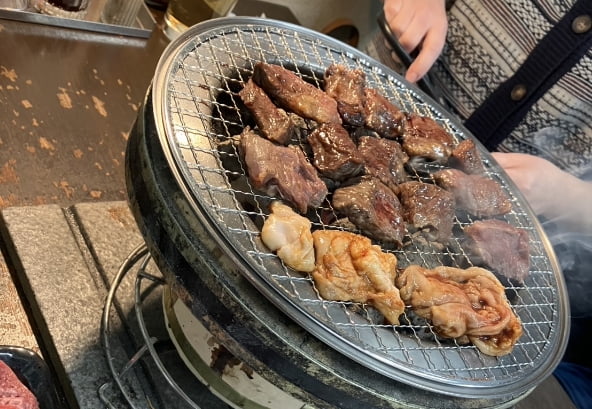 焼肉仁にて焼肉を焼くシーン