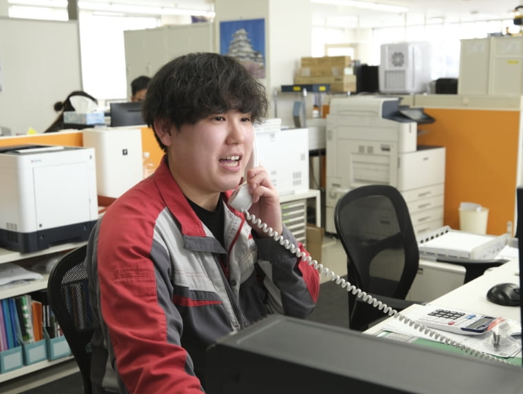 電話対応をする部品課の男性