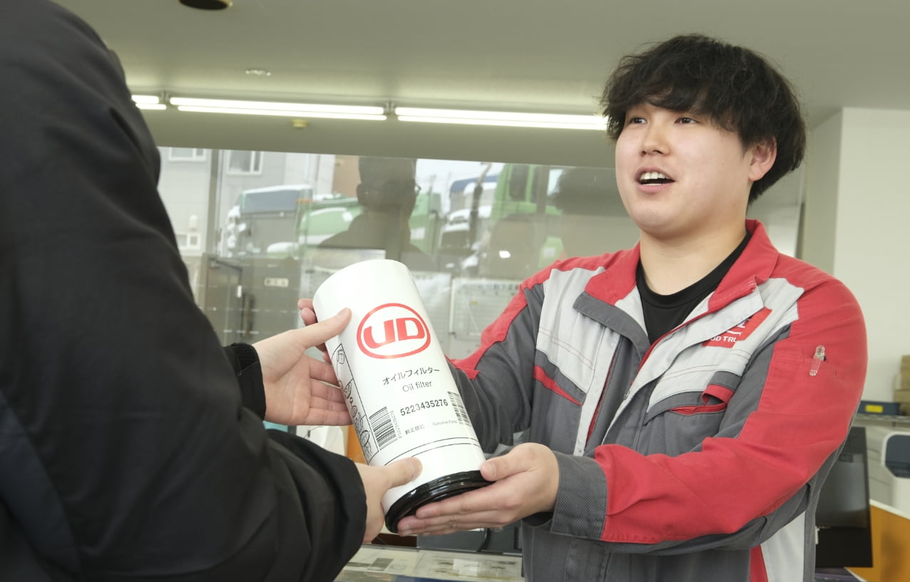 お客様に部品を渡す部品課の男性