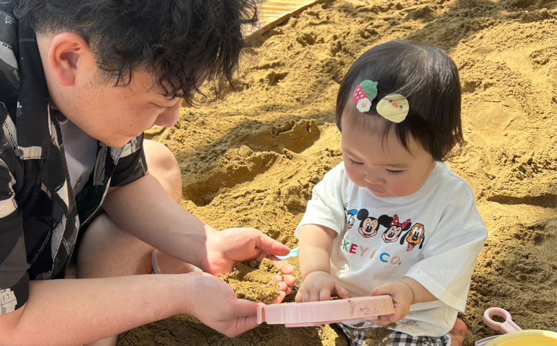父親と子供が砂場で遊んでいる画像