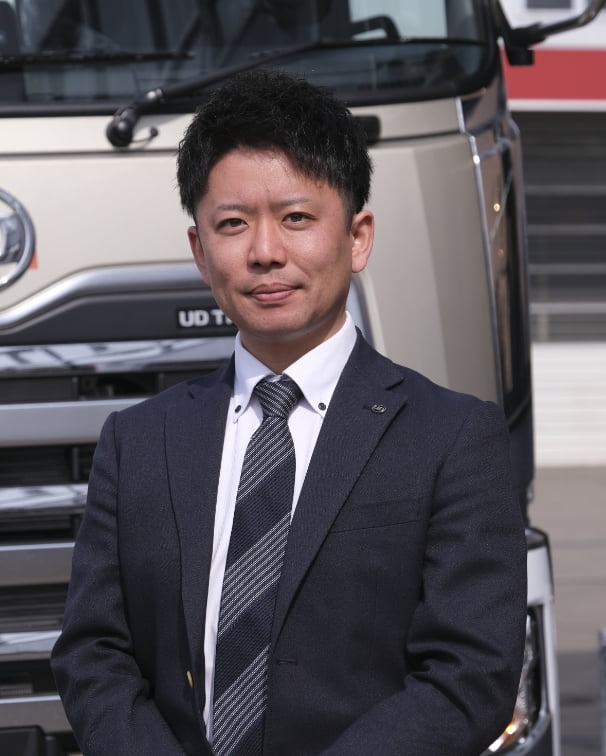 トラックの前で正面を向いている販売課の男性