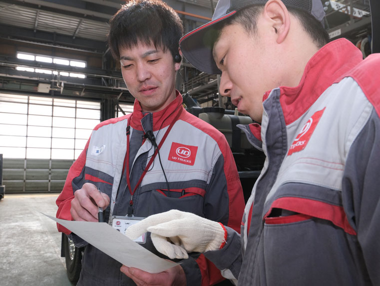 整備工場で打ち合わせを行うメカニックの男性二人