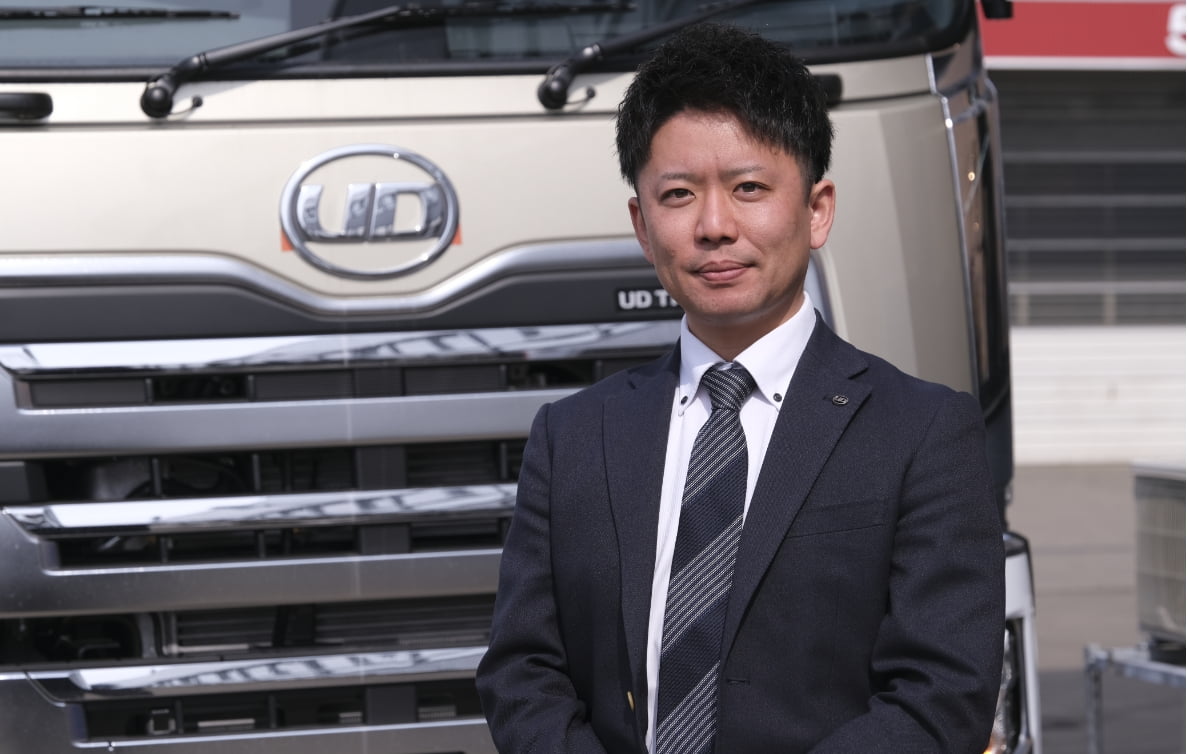 トラックの前で正面を向いている販売課の男性